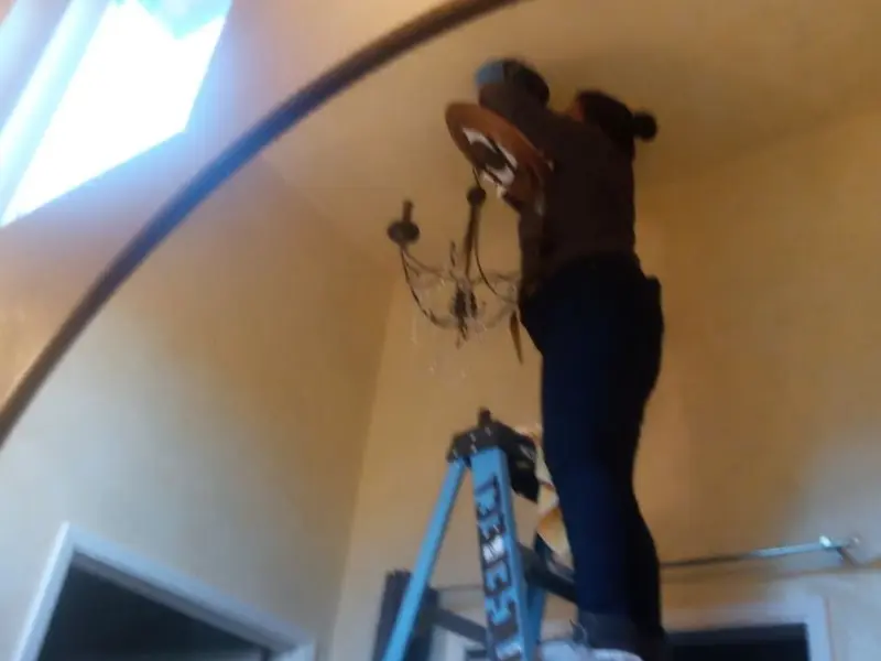 Electrician installing a chandelier in a Grand Rapids residence